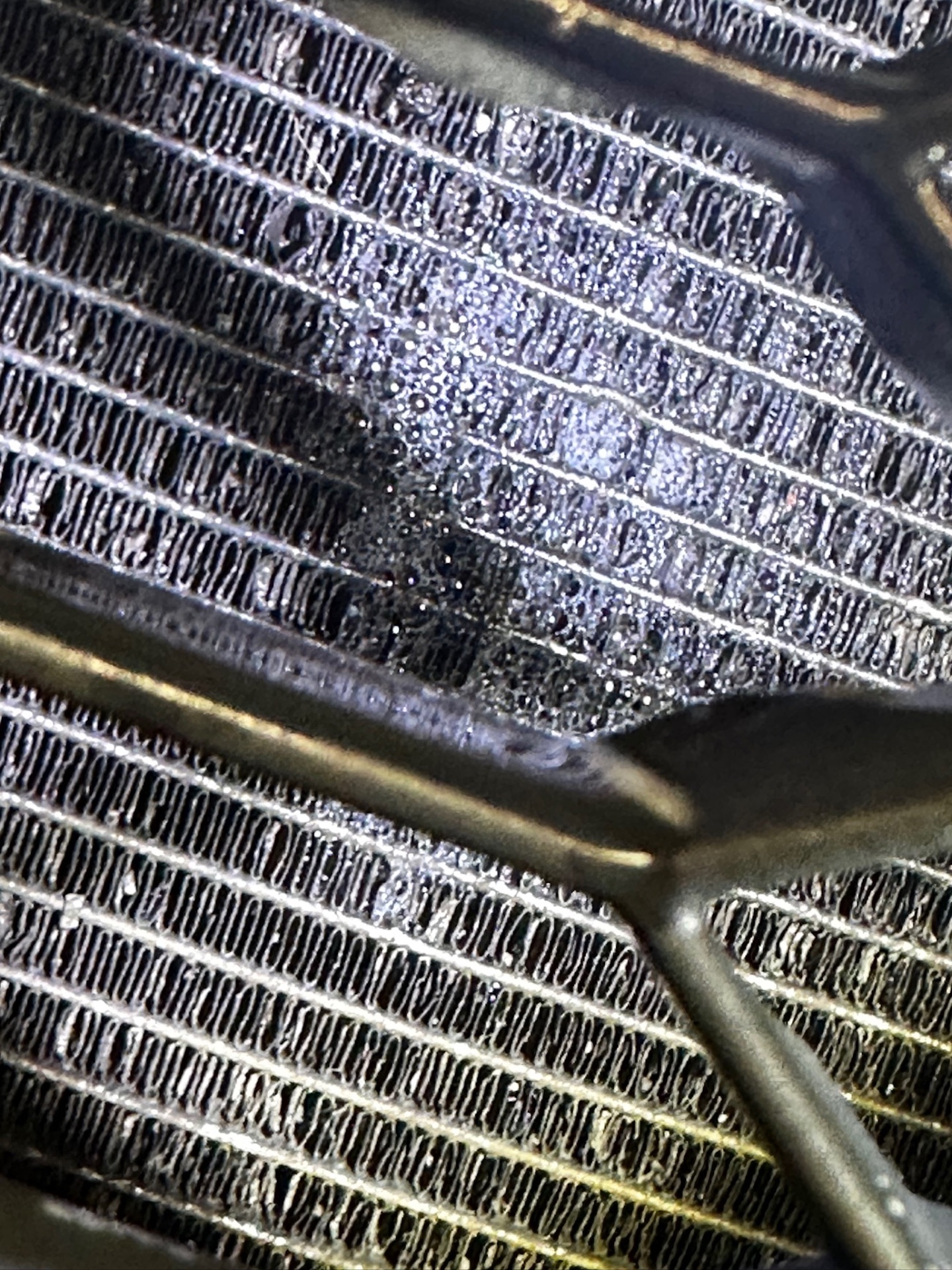Macro shot of condenser fins damaged by road grit and salt corrosion