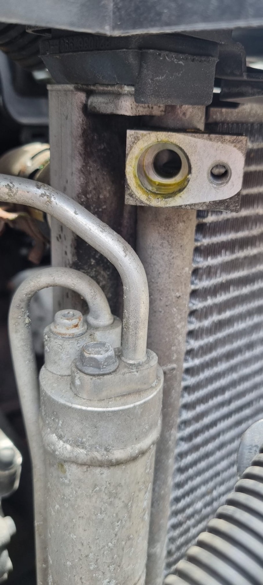 Air conditioning receiver drier and condenser port showing oil residue from a refrigerant leak