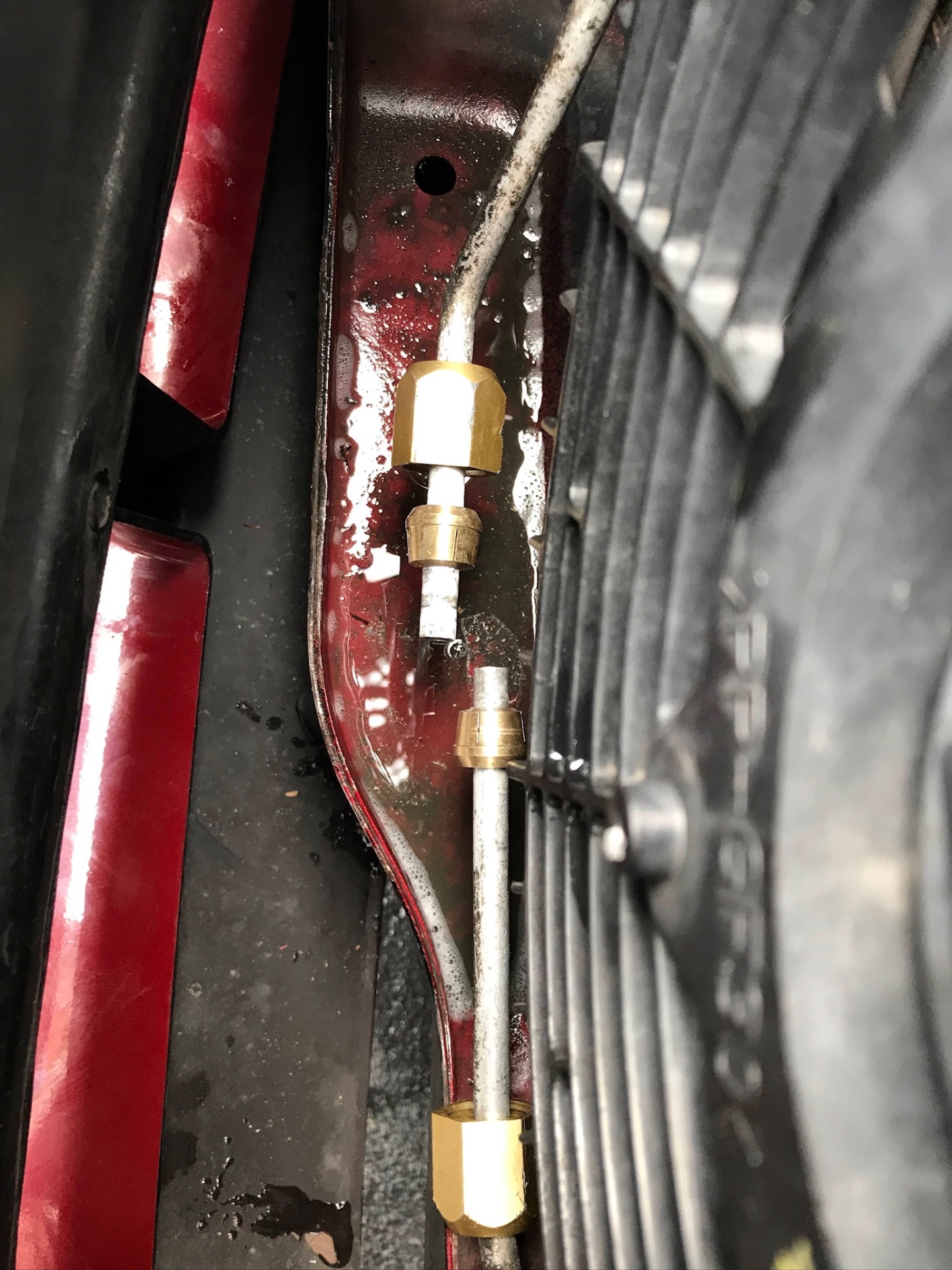 Air conditioning pipe union and condenser during leak testing on a red car