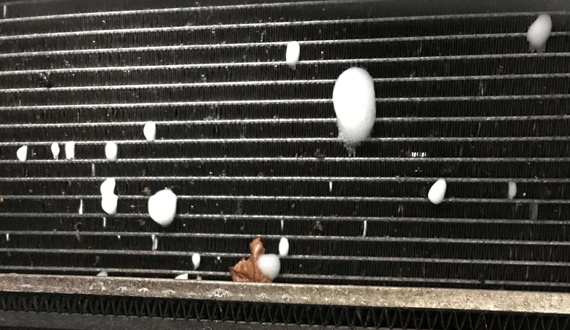 Close up of leak test foam bubbles forming on a car air conditioning condenser core